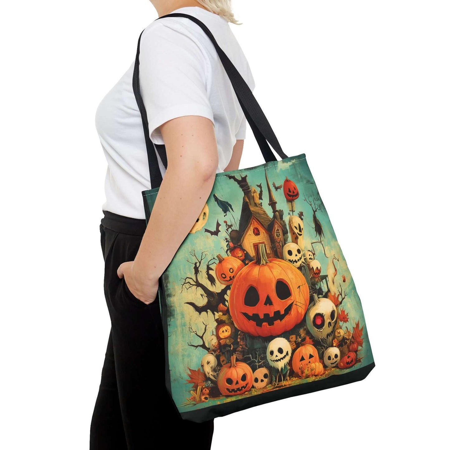 Woman carrying a large tote bag with all-over print of Jack o' lanterns, spooky house, and ghosts, perfect for Halloween.
