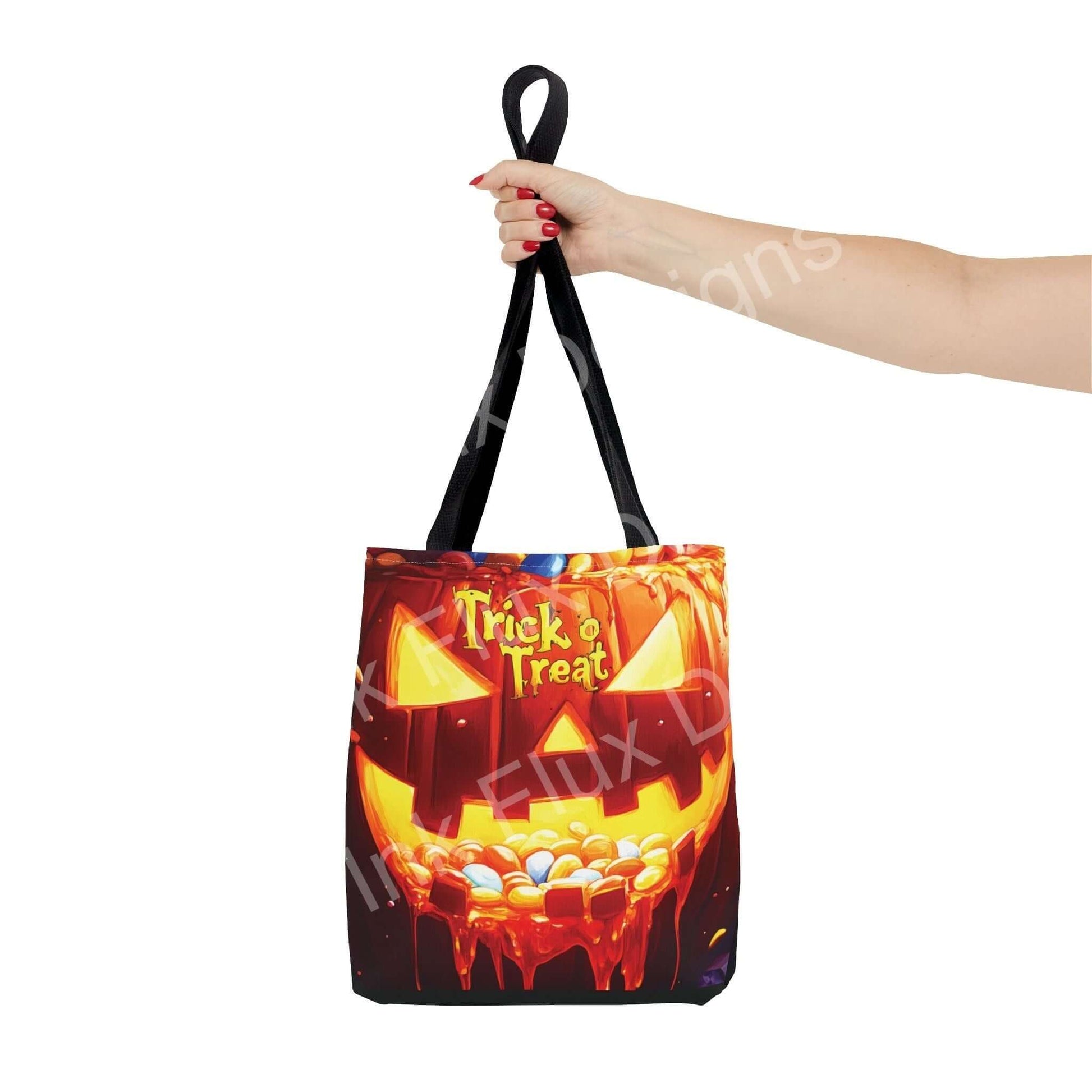 Woman's hand holding a Jack o Lantern II Tote Bag featuring a vibrant "Trick or Treat" design and black handles, perfect for Halloween.