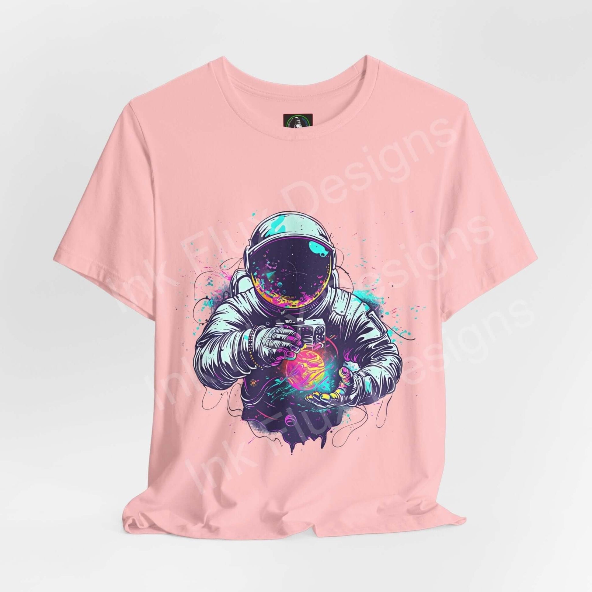 Unisex pink T-shirt featuring bold graphic of an astronaut holding a galaxy, crafted from Airlume cotton, ideal for style and comfort.