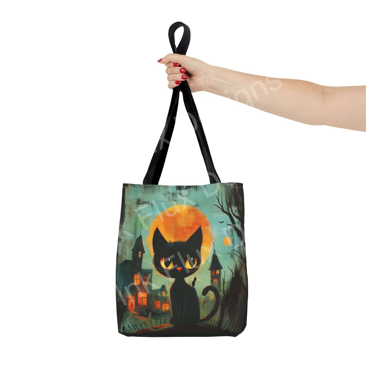 Woman's hand holding a Black Cat Painting Tote Bag with all-over print design, featuring a spooky cat and haunted village motif, crafted from durable polyester.