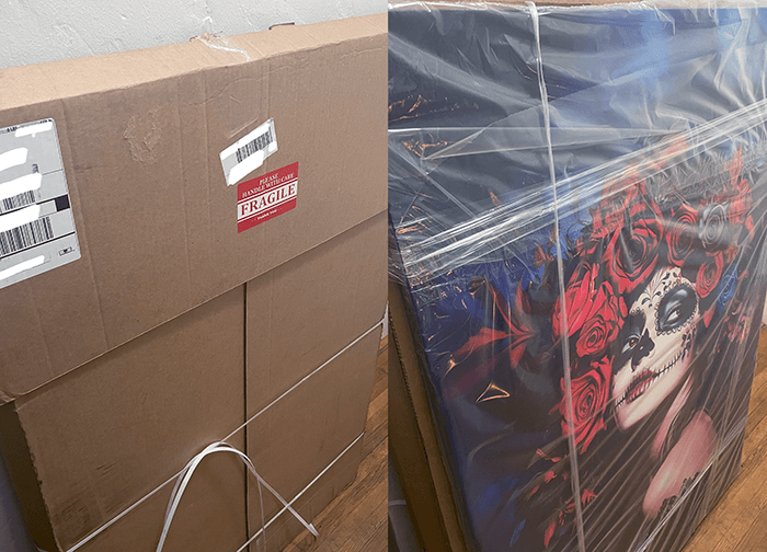 Cardboard boxes labeled 'Fragile' and a wrapped canvas print featuring a colorful skull and roses design.