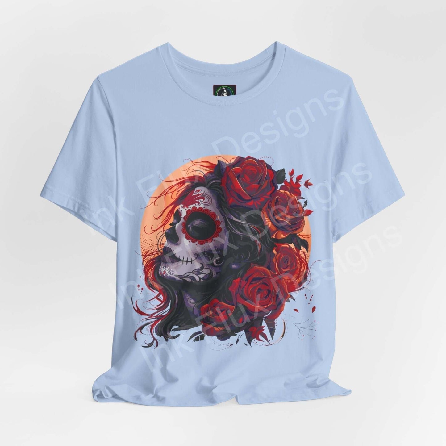Light blue unisex T-shirt featuring a vibrant Day of the Dead graphic with a skull and red roses design, perfect for DÃa de Muertos celebrations.