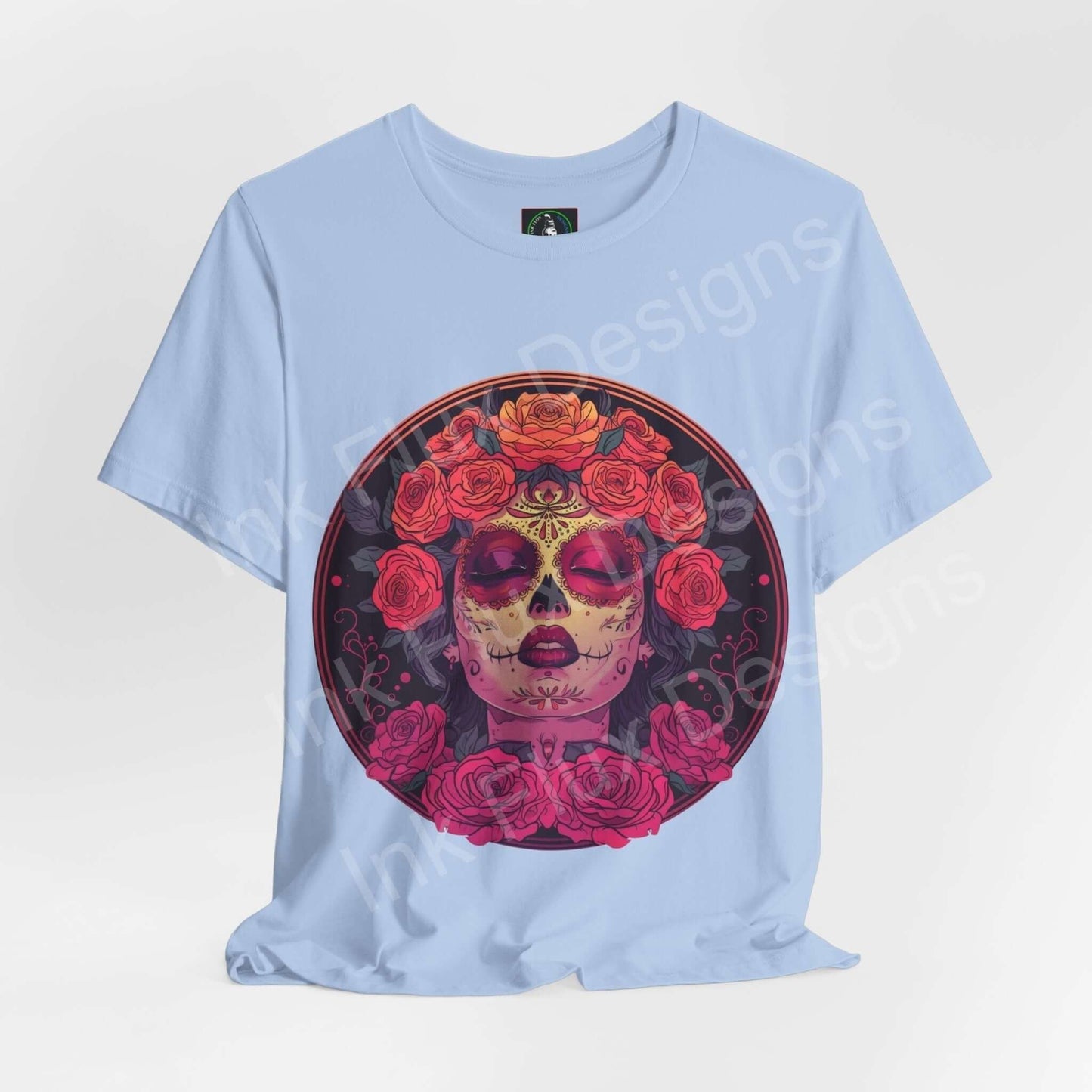 Light blue unisex T-shirt featuring a vibrant Day of the Dead graphic with a skull adorned in red roses, ideal for DÃa de Muertos celebrations.