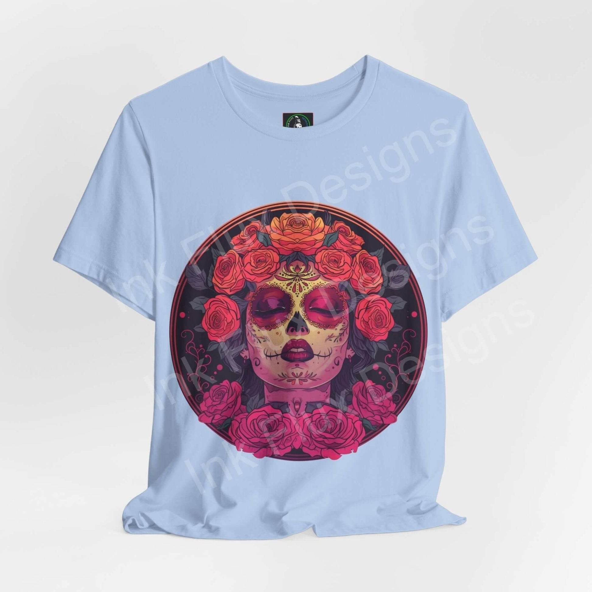 Light blue unisex T-shirt featuring a vibrant Day of the Dead graphic with a skull adorned in red roses, ideal for DÃa de Muertos celebrations.