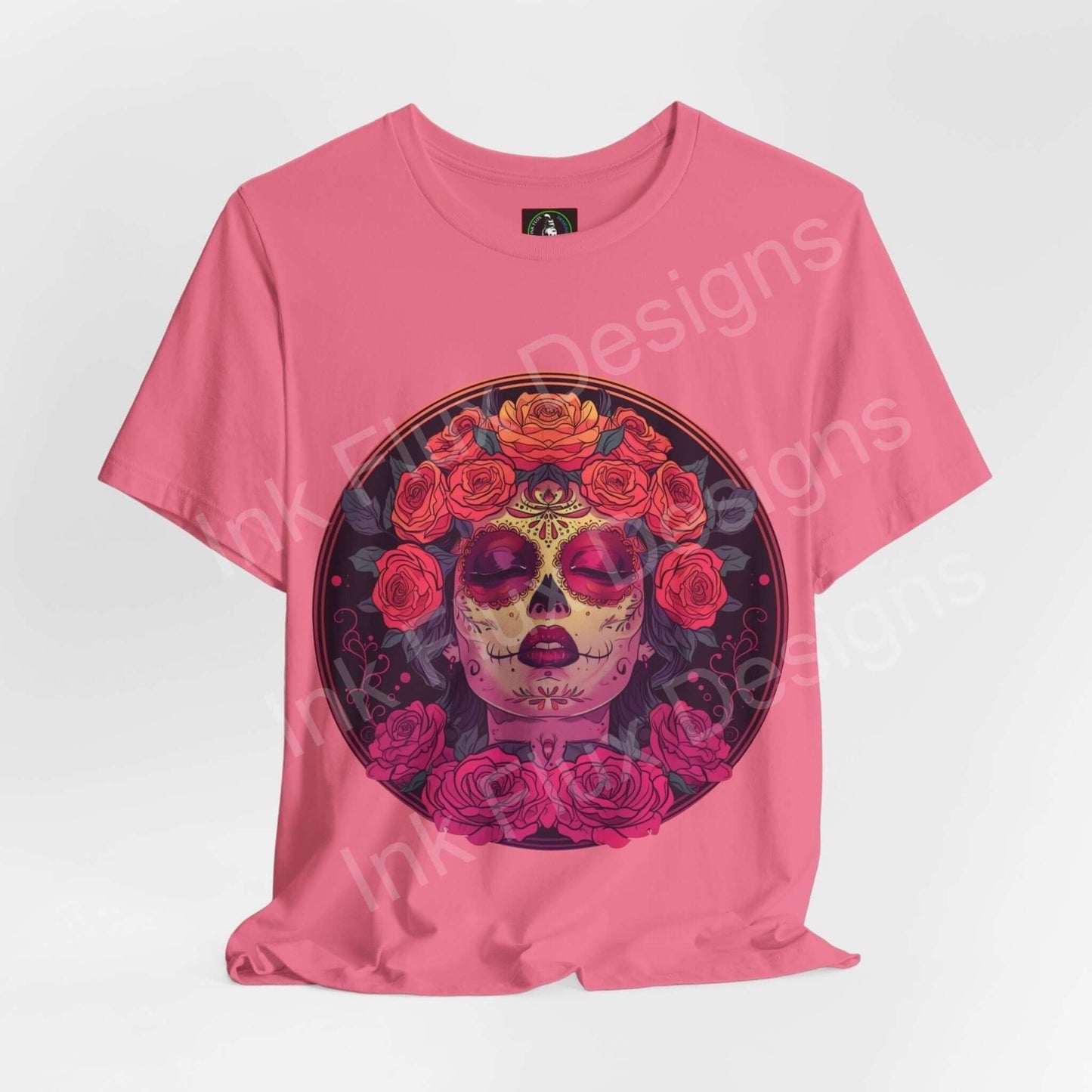 Pink T-shirt featuring a vibrant Day of the Dead graphic with a skull adorned with roses, symbolic of DÃa de Muertos celebrations.