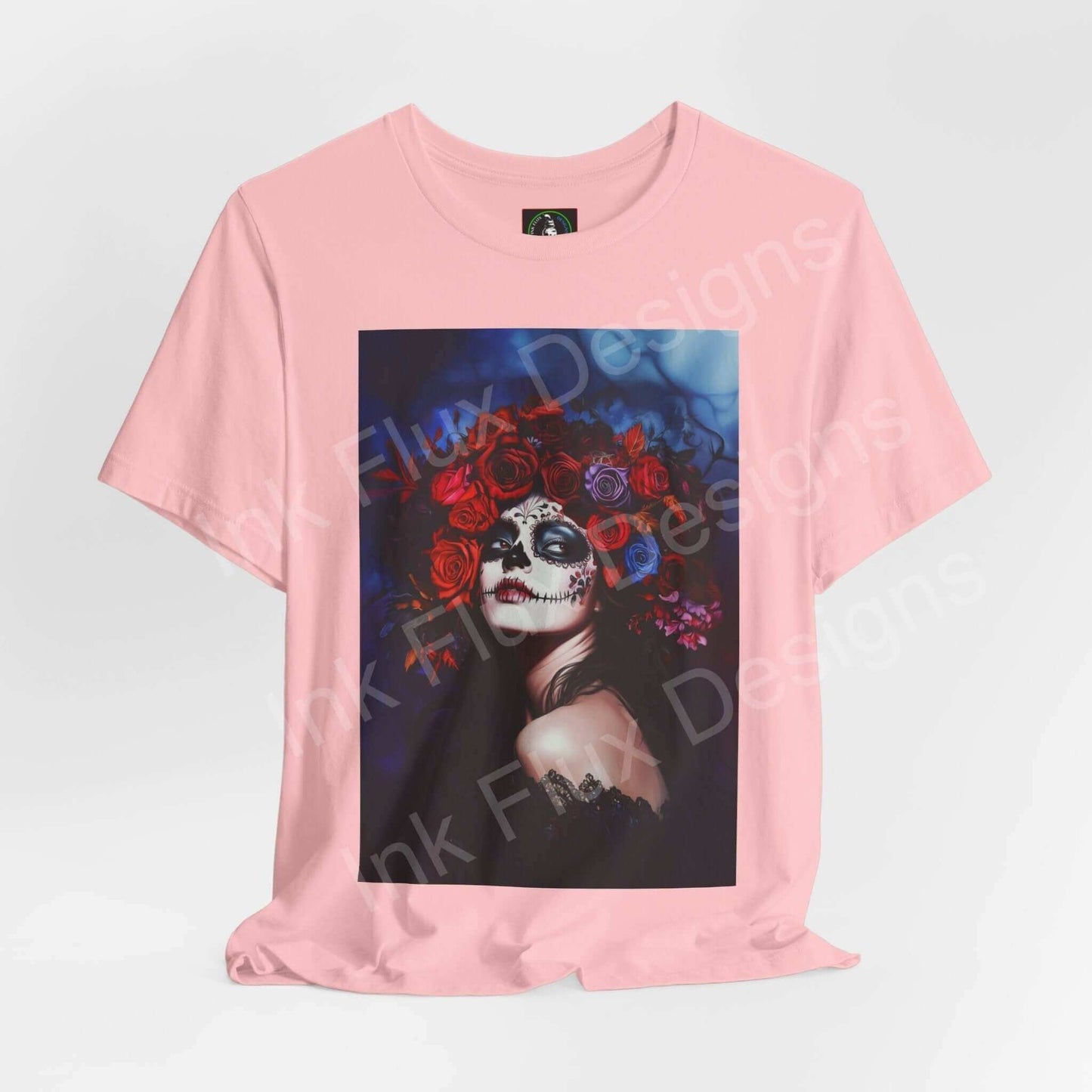 Pink T-shirt featuring a Day of the Dead themed graphic with a woman's portrait adorned with a floral crown, emphasizing DÃa de Muertos style.
