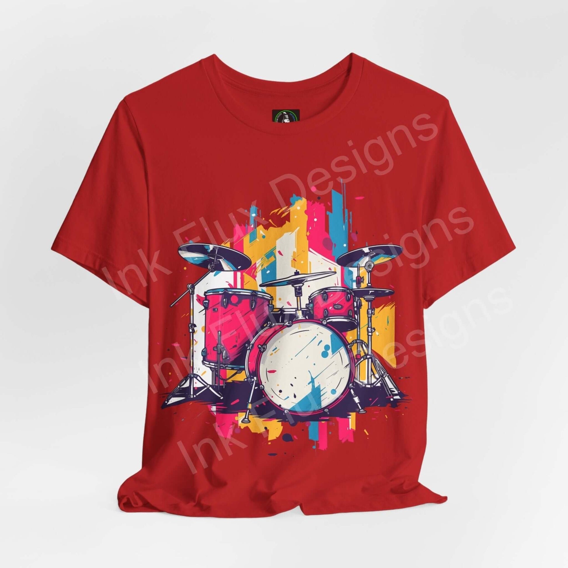 Red unisex jersey T-shirt featuring a bold graphic of a drum set with vibrant splashes of paint, crafted from soft Airlume cotton.