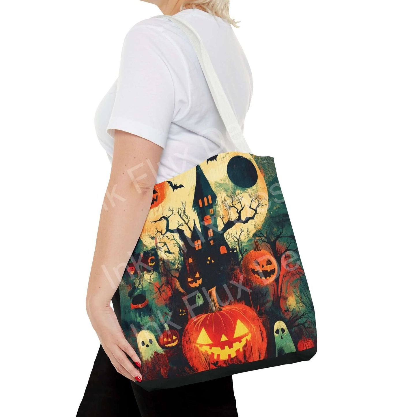 Woman showcasing a Halloween-themed tote bag featuring a spooky haunted house, pumpkins, and ghosts design.