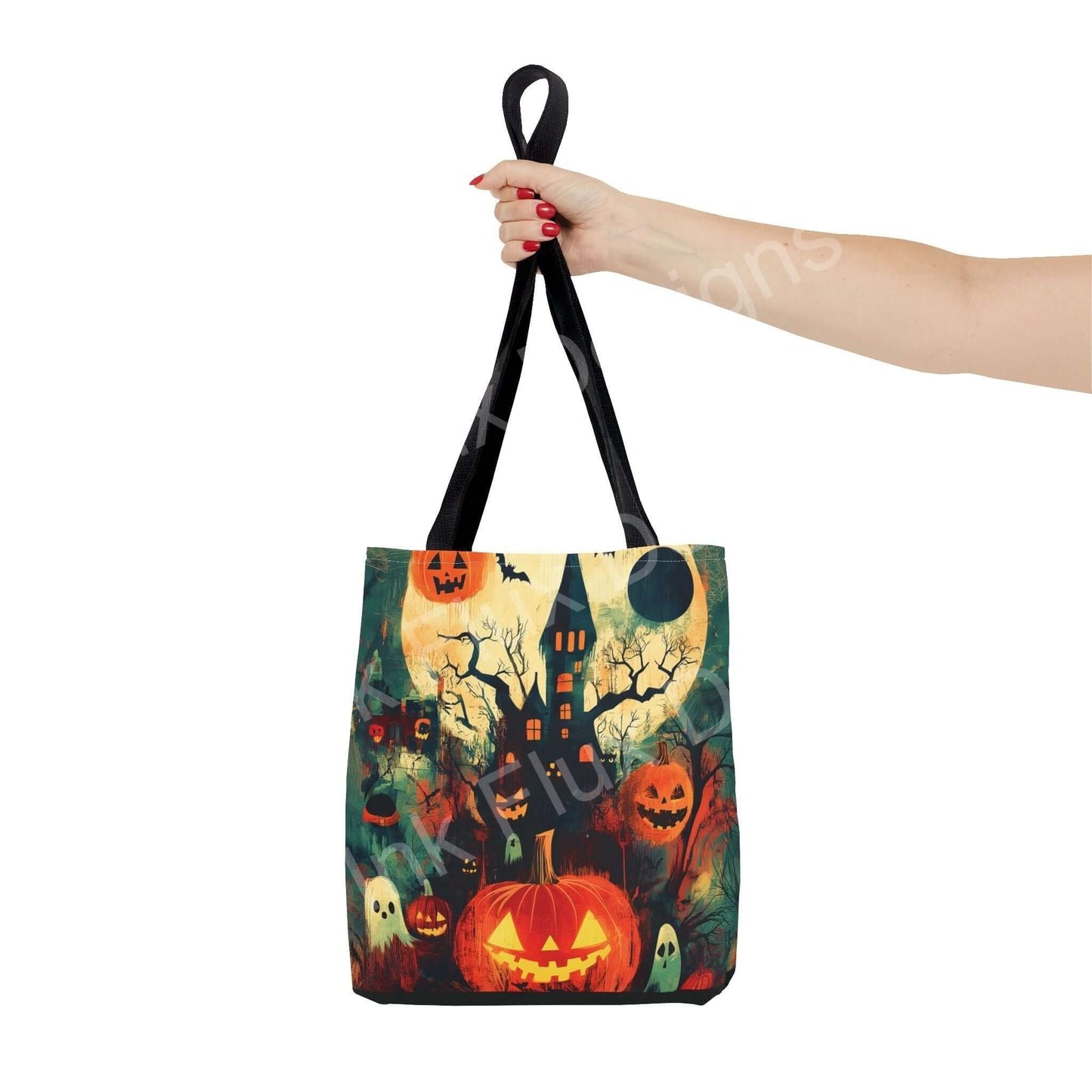 Woman holding a Halloween-themed tote bag featuring a spooky design with pumpkins, haunted house, and full moon.