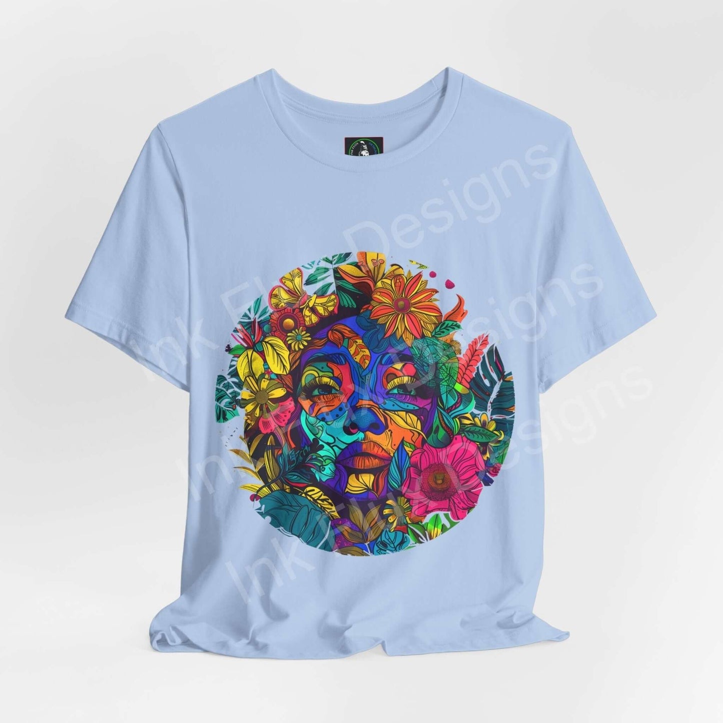 Light blue unisex jersey T-shirt featuring a bold, psychedelic graphic of a colorful Mother Earth face surrounded by flowers, crafted by Bella+Canvas.
