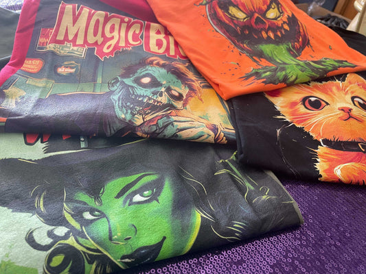 Assortment of Halloween themed t-shirts featuring spooky characters and vivid colors displayed on a purple background.