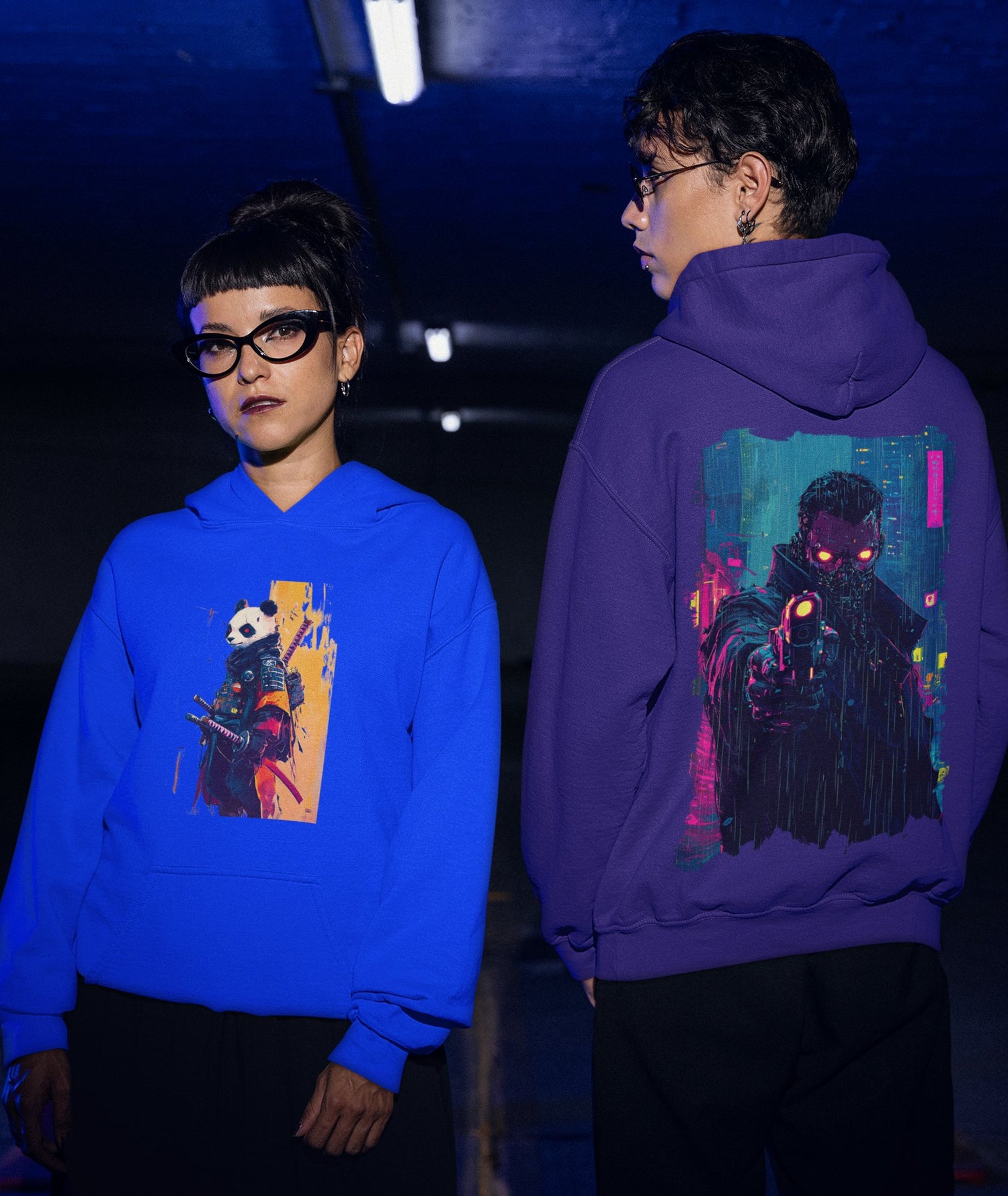 Two models showcasing Ink Flux Hoodies, one in blue with a spirit animal design and another in purple with a cyberpunk motif.