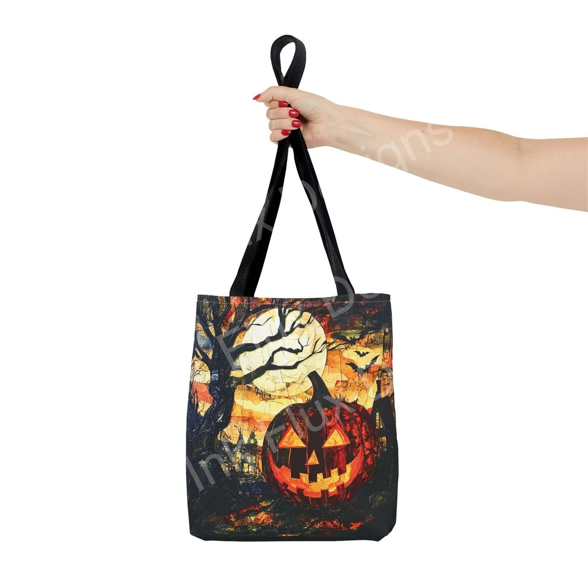 Woman's hand holding a Jack o Lantern painting tote bag, featuring vibrant Halloween-themed all-over print on polyester fabric with black straps.