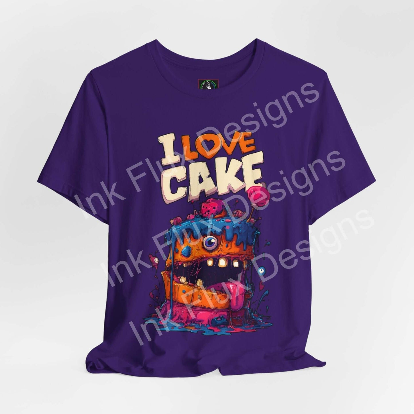 Funny Graphic T-Shirt featuring a cartoon monster cake with colorful icing and oversized eyes on a purple background.