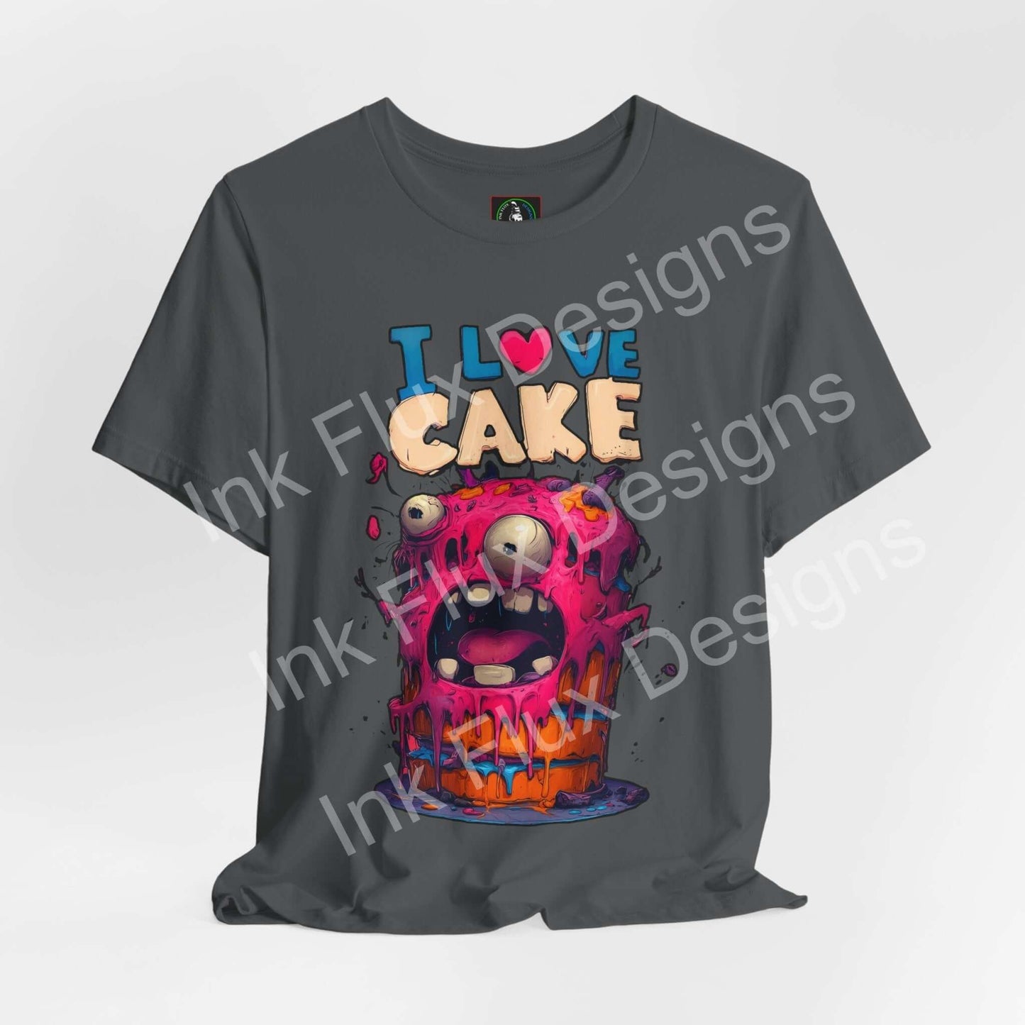 I Love Cake Funny Graphic T-Shirt featuring a cartoon monster cake design with colorful frosting and big eyes.